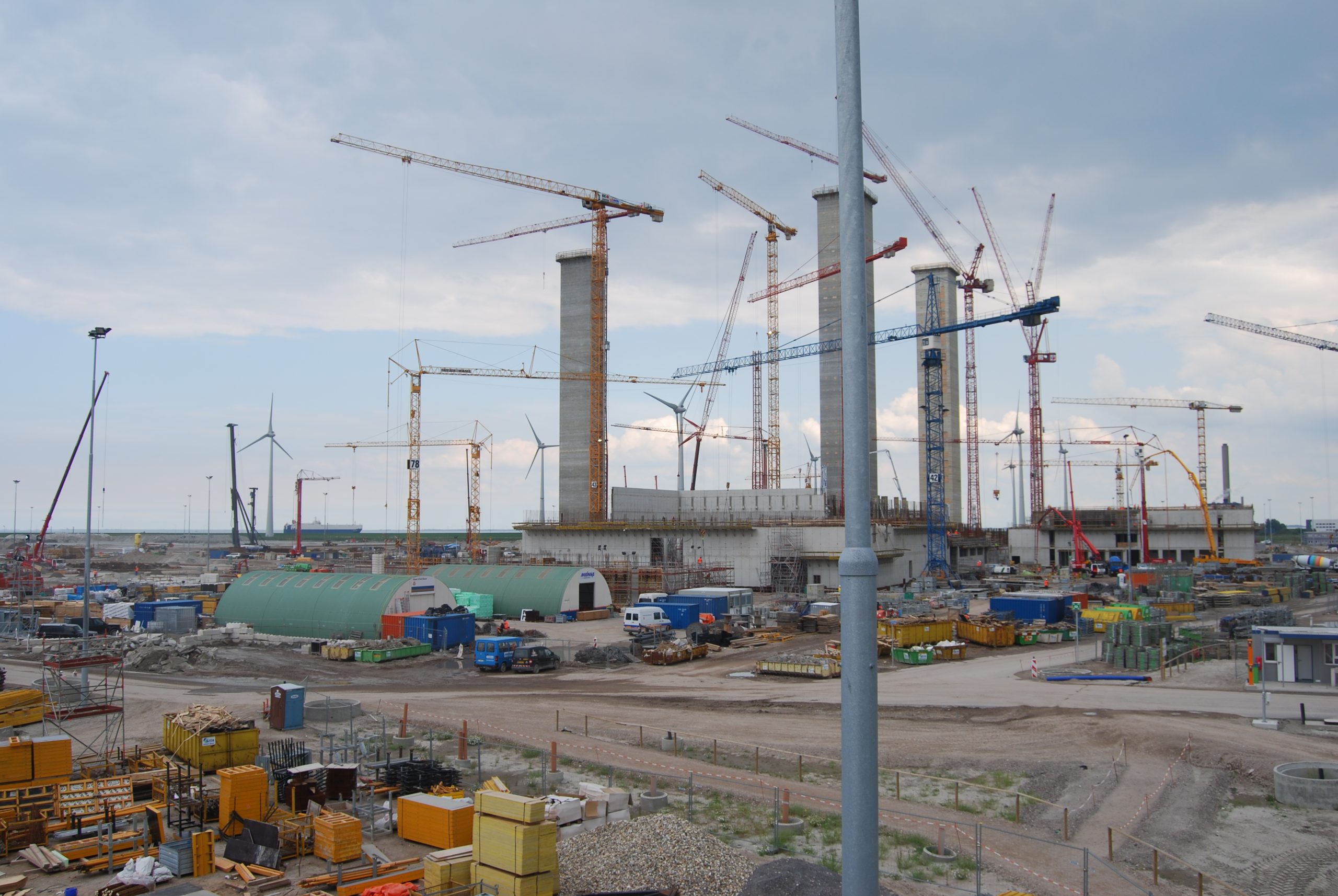 Grote bouwplaats met meerdere torenkranen en betonnen silo’s