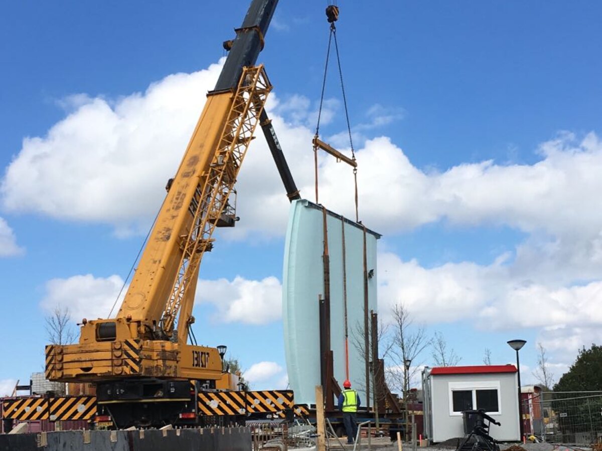 Mobiele kraan stelt een prefab betonelement op de bouwplaats